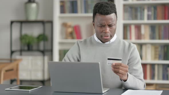 African Man Making Online Payment Failure on Laptop in Library