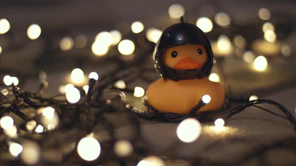 Closeup Shot of Rubber Duck in Hand Made Motorcycle Helmet on Background of Christmas Garland