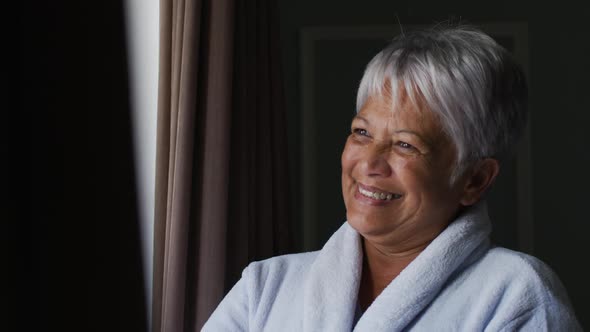 Senior mixed race woman at home waving out of window