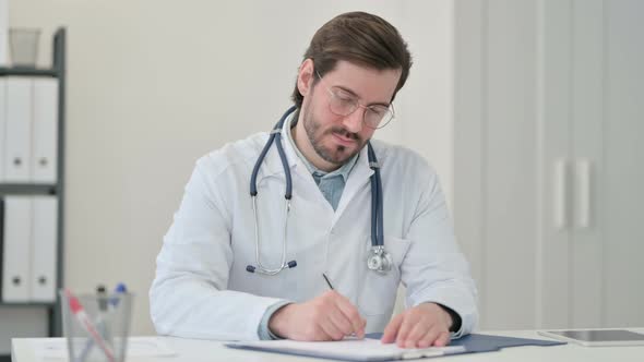 Young Male Doctor Writing Paper Work