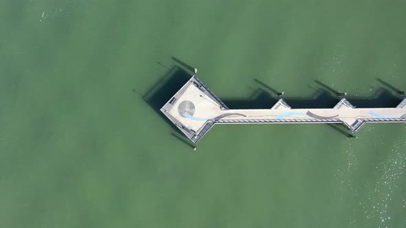 A top down shot high over a pier in the green water in Red Hook Channel on a sunny day. The camera b