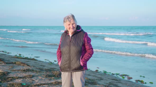 Elderly Woman Stands on Wet Sand Beach Enjoying Weather