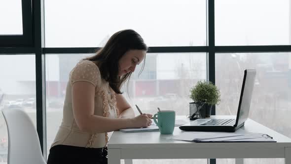 Young Woman Working in Office and Taking Notes