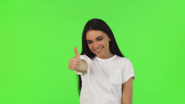 Happy Beautiful Woman Showing Thumbs Up on Green Background