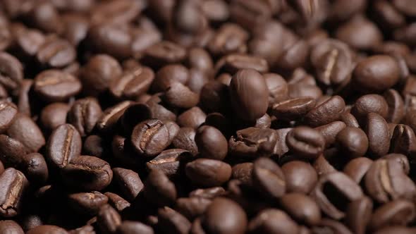 Freshly roasted coffee beans or coffee grains fall on a wooden table on a brown background at cafe.