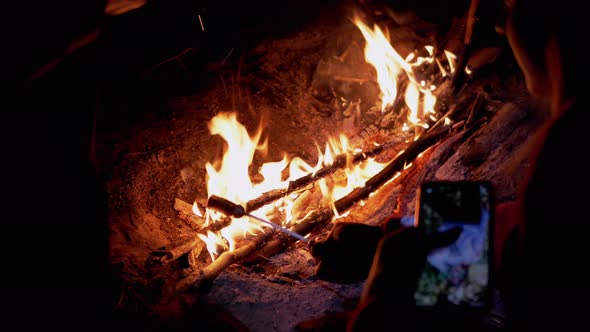 Hungry Tourists Grilling Sausages on Wooden Skewers Sits By Night Bonfire