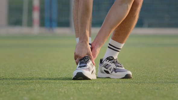 Closeup of Strong Male Legs in White Sneakers and Socks on Grass of Sport Stadium
