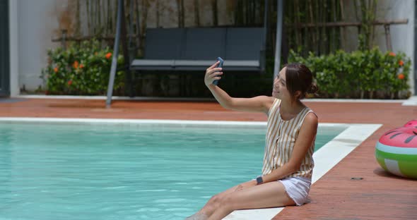 Woman use of mobile phone and sit at the swimming pool