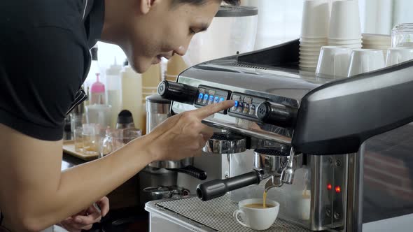 Male barista press espresso machine, waits and brings up coffee cup, and smell