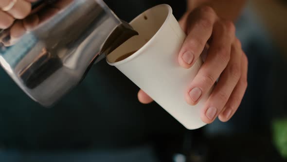 Barista Drawing cappuccino Coffee Art on cardboard cup Coffee with vegetable Milk.