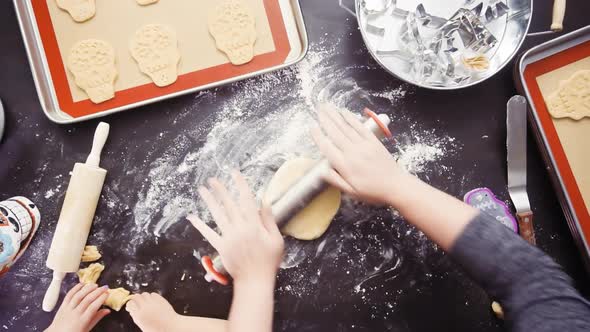 Flat lay. Mother and daughter baking sugar skull cookies for Dia de los Muertos holiday.