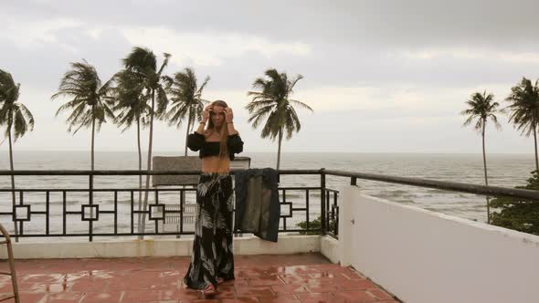 Long haired blonde Russian model posing in front of the camera while on a rooftop along the ocean in