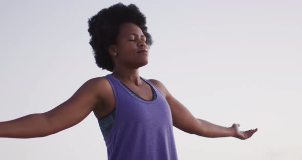 Happy african american woman with arms wide on sunny beach