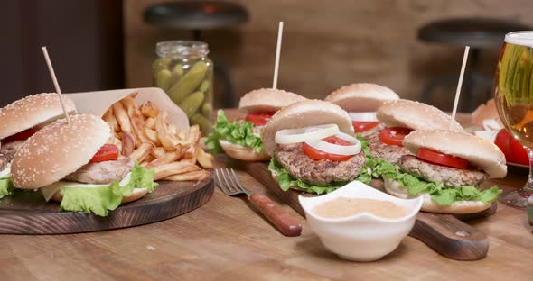 Smooth Parallax Shot of Wide Selection of Burgers on a Wooden Round Table