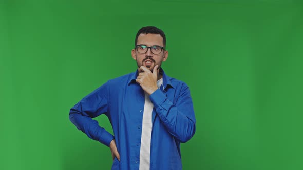 Pensive Young Bearded Man Looking for Solutions to Problems Over Green Background Isolated