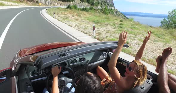 Handsome black man sticking his feet up of convertible riding with his friends