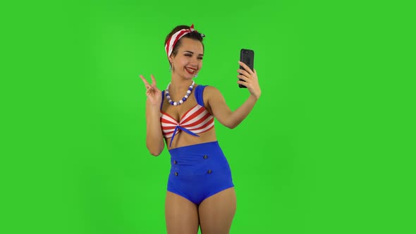 Beautiful Girl in a Swimsuit Is Making Selfie on Mobile Phone Then Looking Photos. Green Screen