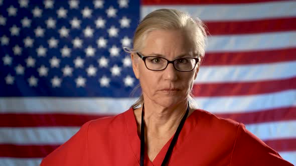 Portrait of a nurse showing a seriousness and disapproval set against an out of focus US flag.