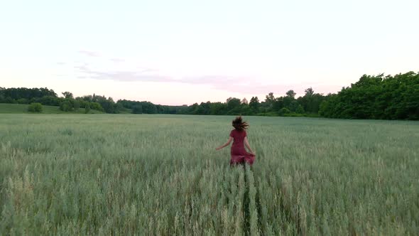 Young Woman with Long Hair in Long Dress Runs on a Field, Slow Motion  Shot