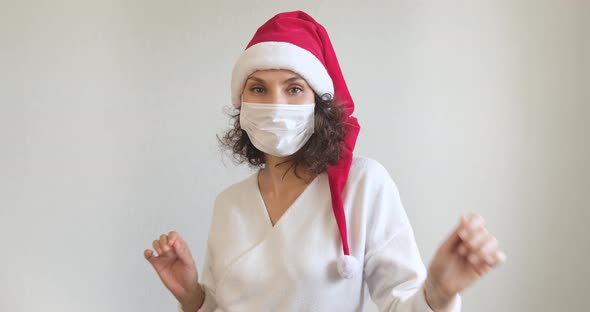 Young Woman in Medical Mask and Santa Claus Hat Dancing and Having Fun. Close Up of Female in