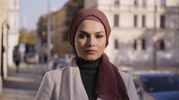 A Young Beautiful Muslim Woman Looks Seriously at the Camera in a Street in an Urban Area  Closeup