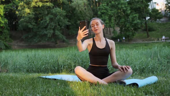 Woman Sits on a Fitness Mattress Talking on Video Online Chat Yoga Classes