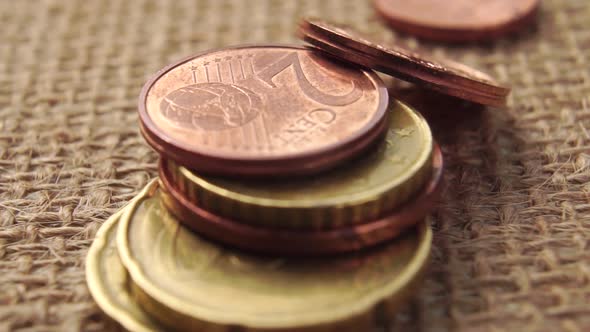 Euro cents coins fall on a brown sackcloth. 