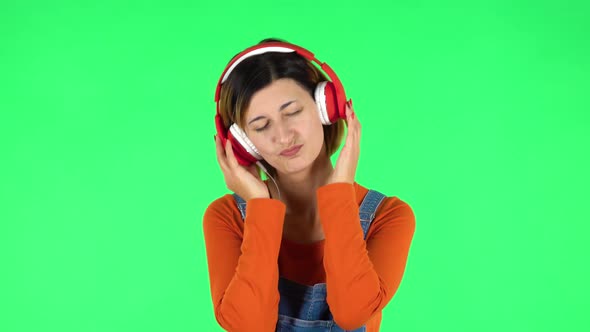 Cheerful Girl Dancing and Enjoys Music in Big Red Headphones. Green Screen