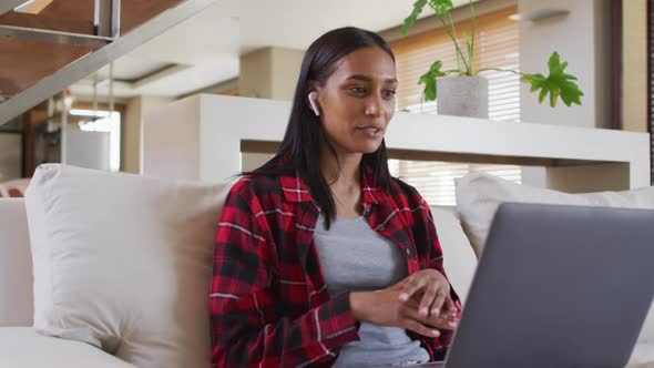 Mixed race woman on couch at home using laptop having video chat