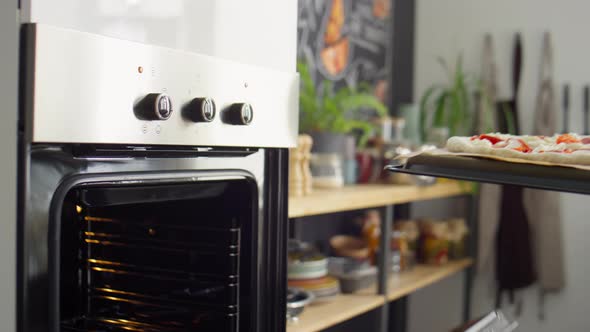 Man Putting Pizza in Oven for Baking