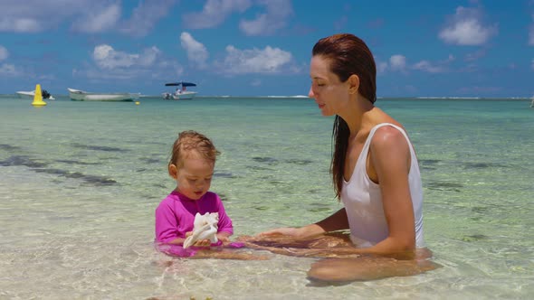 Mom and Her Daughter are Playing in the Clear Water on the Shore of the Indian Ocean