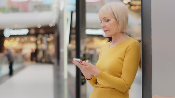 Smiling Middle Aged Mature Caucasian Woman Holding Phone Looking at Smartphone Screen Sending