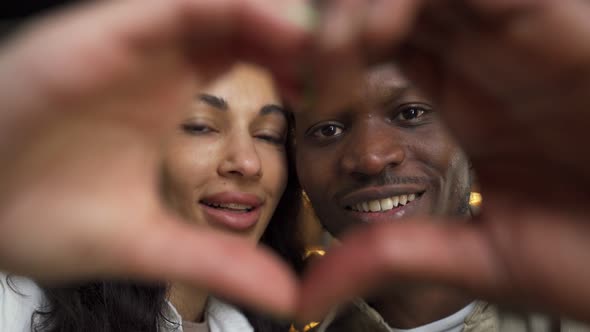 Happy Couple in Love Makes Shape of Heart with Fingers