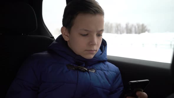 Young Boy Using Smartphone During Taxi Ride in City