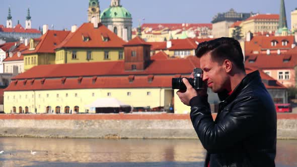 A Young Handsome Man Takes Photos of a Qauint Town with a Camera - a River and Buildings