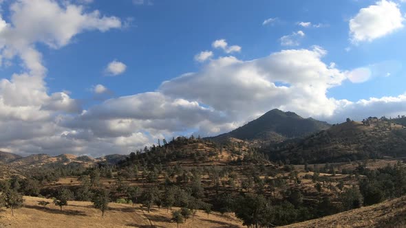 Timelapse, train passing through Tehachapi Pass railway on sunny day with clouds