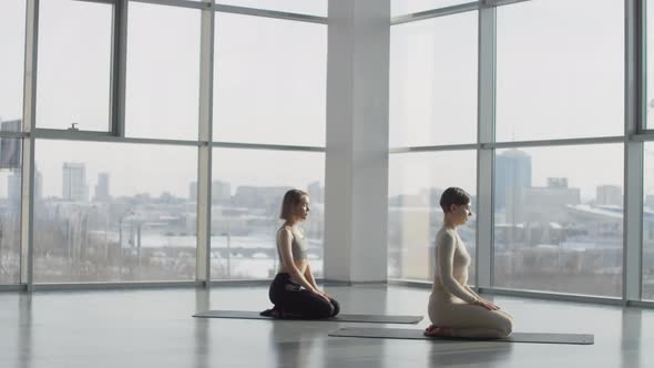 Two Women Sitting On Mats