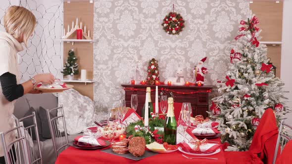 Young Beautiful Woman Preparing Dinner Table for Christmas Celebration
