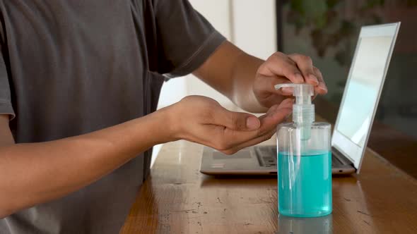 Asian man using hand sanitizer by pumping alcohol gel and washing before start to work 