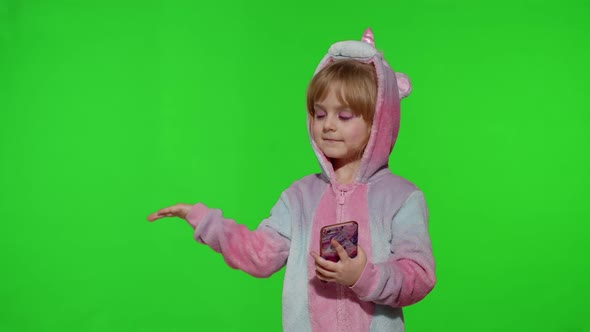 Child Girl in Unicorn Pajama Using Holding Smartphone Pointing at Something with Hands Copy Space