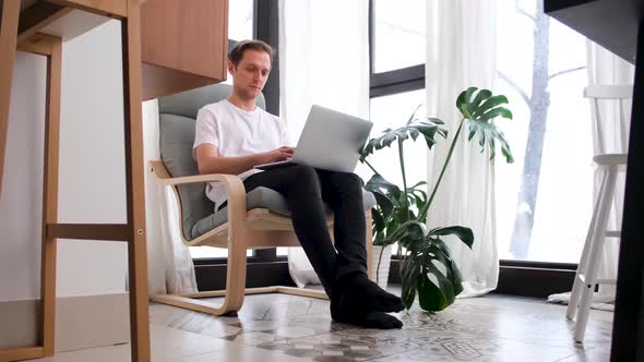 Man Working Using Laptop at Home While Sitting in Chair