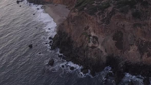 AERIAL: Flight Over Malibu, California View of Beach Shore Line Pacific Ocean at Sunset with