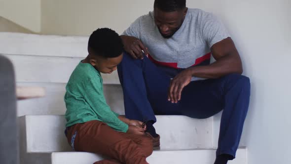 African american father and son sitting on the stairs talking and smiling