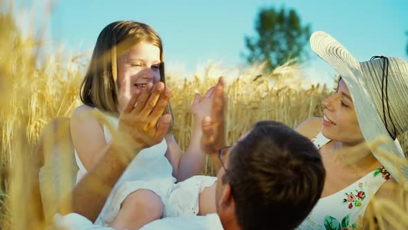 Little daughter clapping hands with father on family picnic in countryside