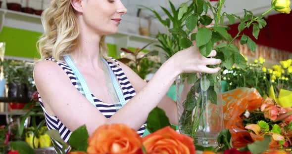 Female florist arranging roses in flower vase at flower shop