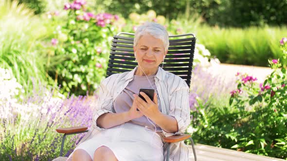 Old Woman with Earphones and Smartphone at Garden