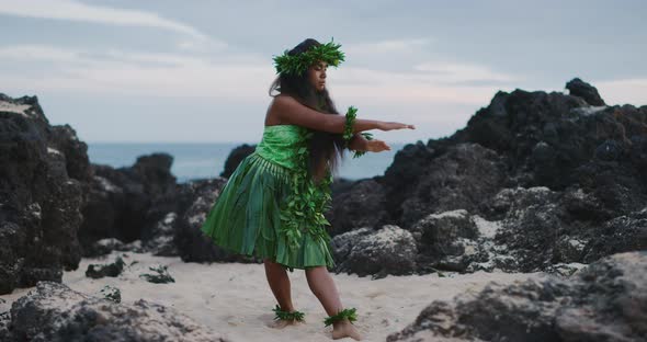 Woman performing traditional Hawaiian hula by the ocean alt