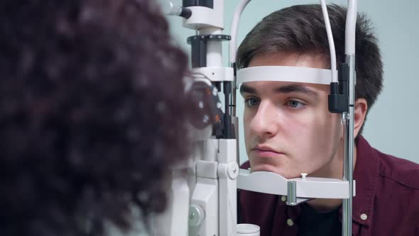 Portrait of Concentrated Man Sitting at Retina Camera As Woman Checking Back of the Eye