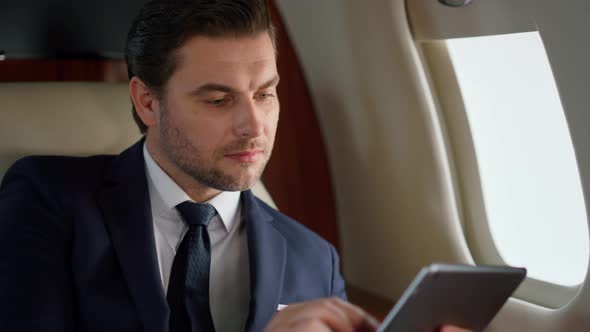 Stylish Manager Using Pad Computer in Airplane Closeup