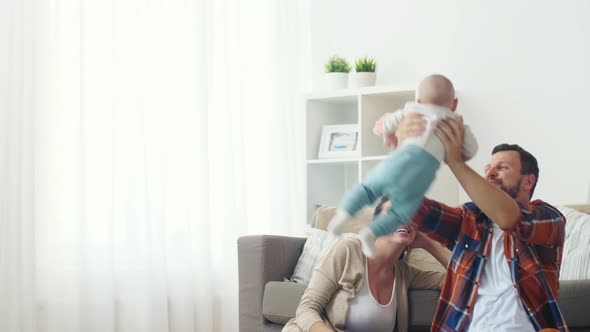 Happy Mother and Father Playing with Baby at Home